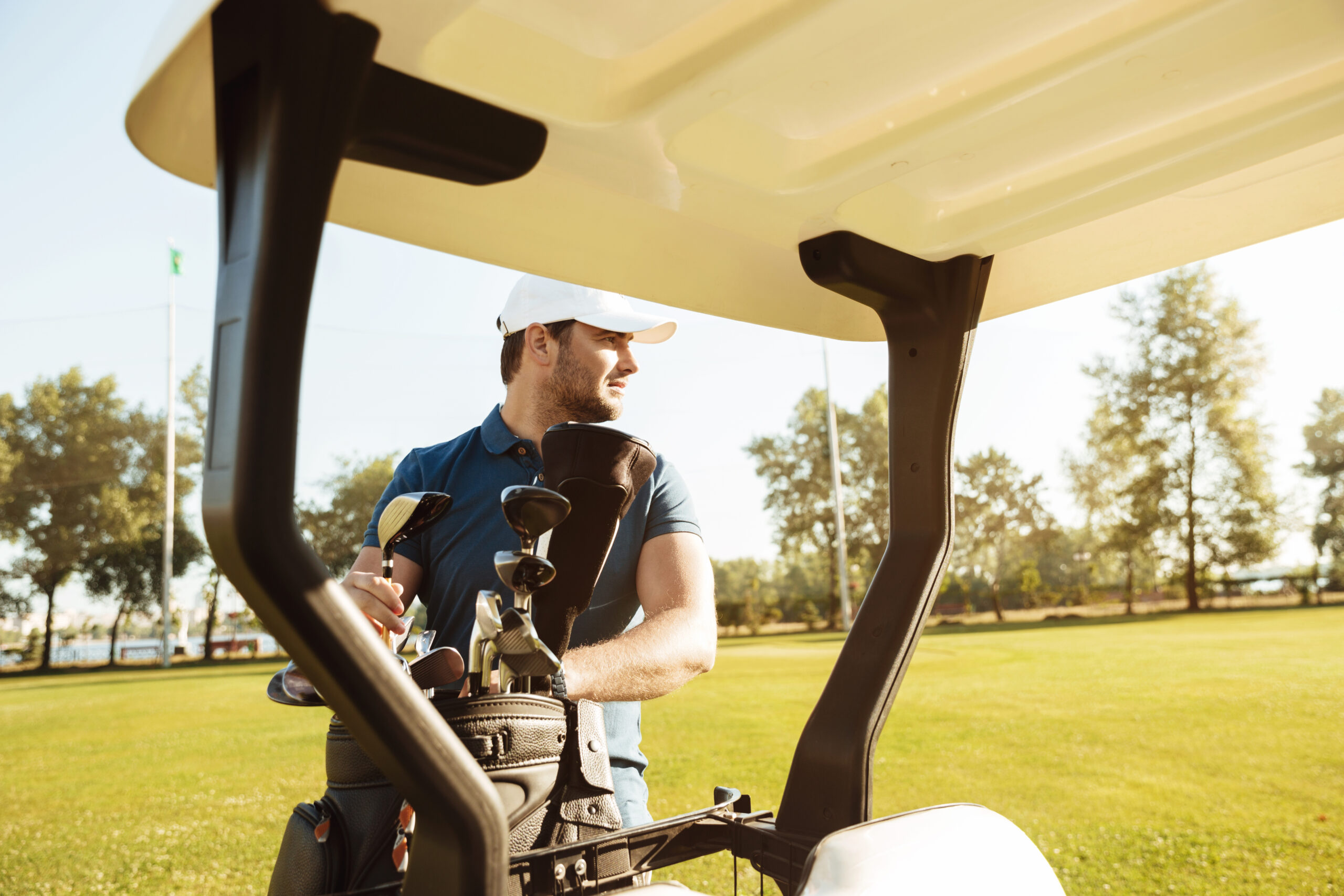 Golfer taking clubs from a bag in a golf cart Driven Fit